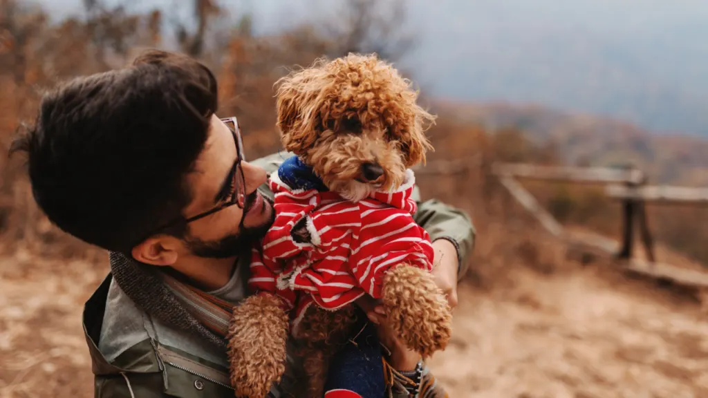 a man holding a small dog in his arms.